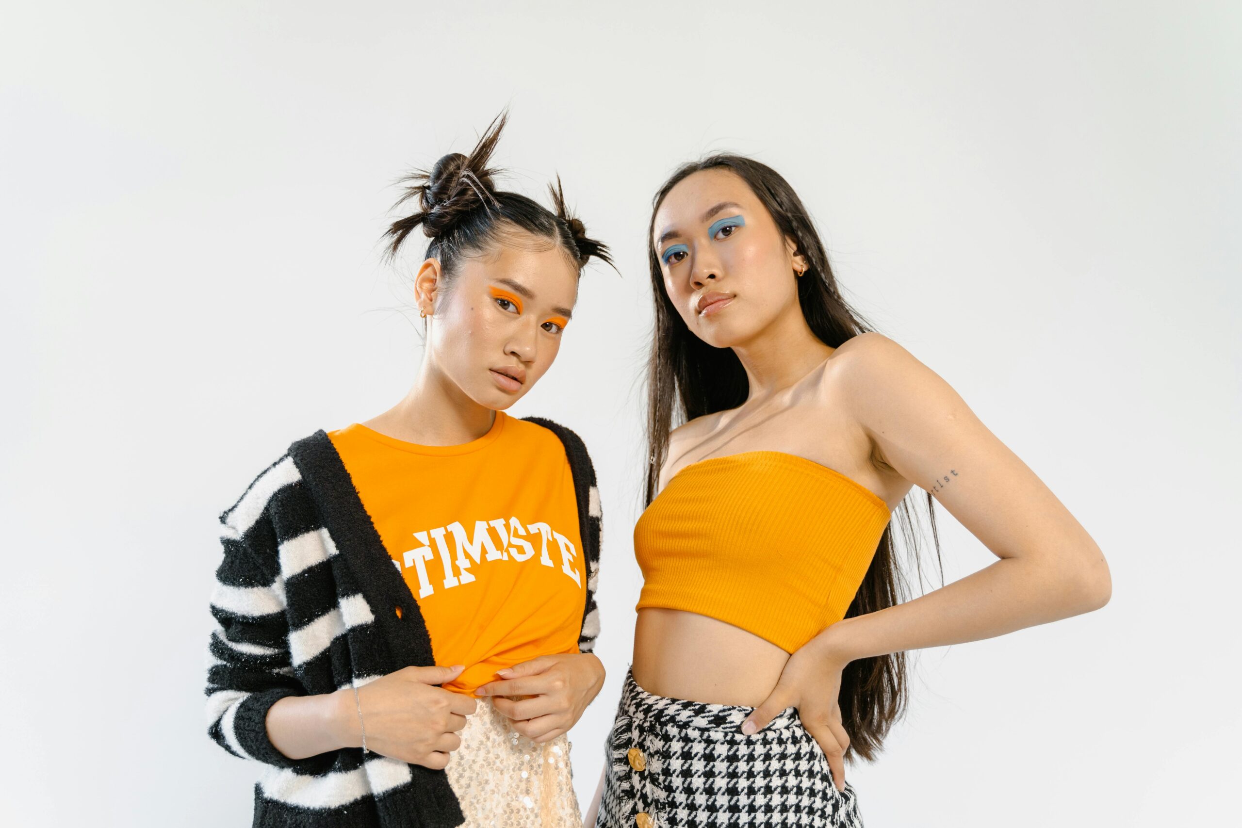 Stylish duo in vibrant outfits posing confidently in a studio.